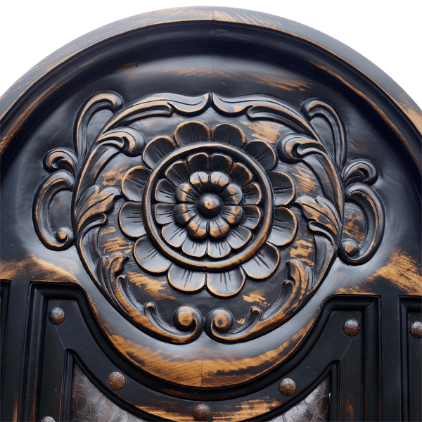 Detail of headboard scroll carving and iron conchos on solid wood
