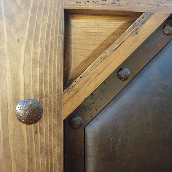 Detail of iron conchos, iron molding, and smooth leather panel on Western-style bed