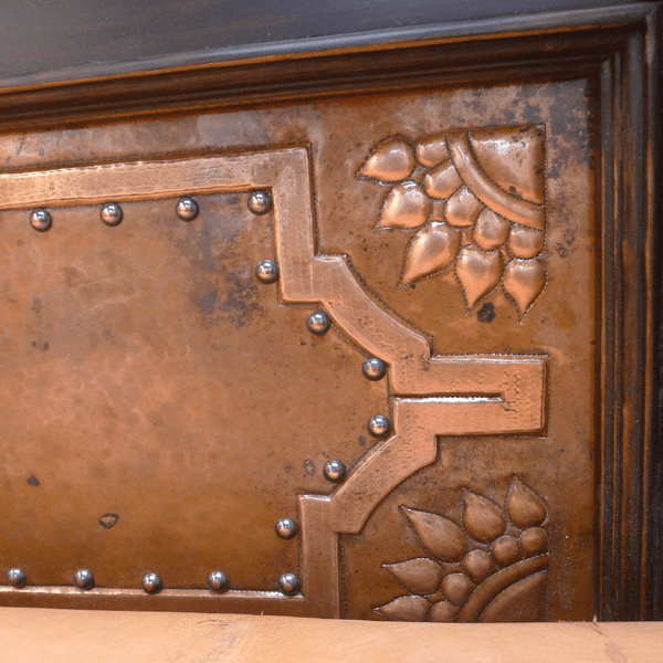 Detail of hand-tooled copper panel with geometric and floral designs on Spanish colonial bed