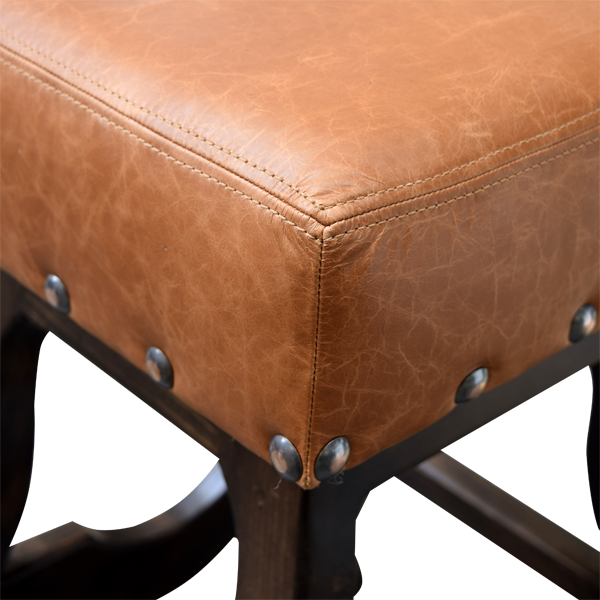 Detail of leather upholstery with double stitching, decorative nails, and wood tone